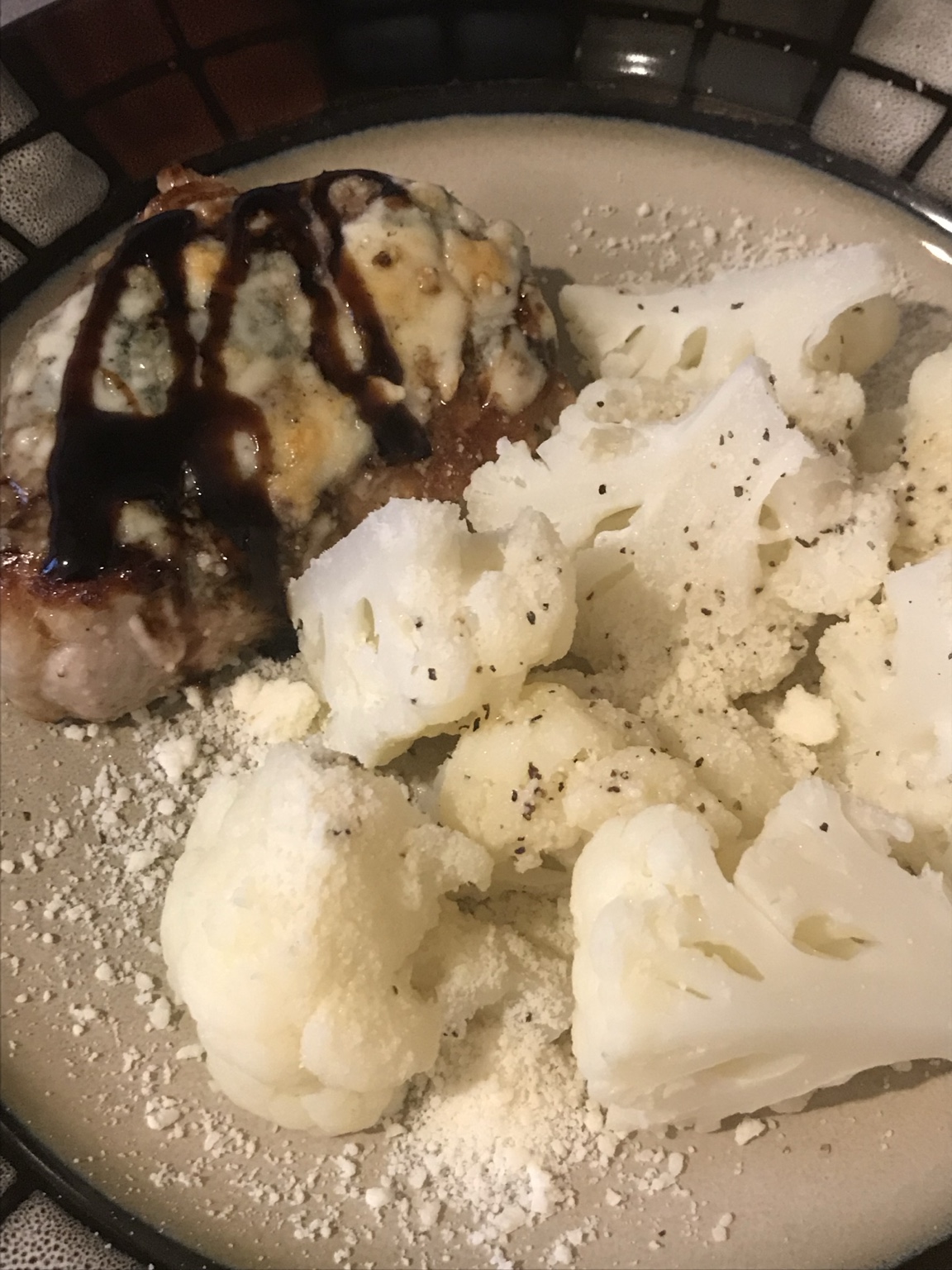 Pork chop topped with melted blue cheese and balsamic glaze, served with cauliflower