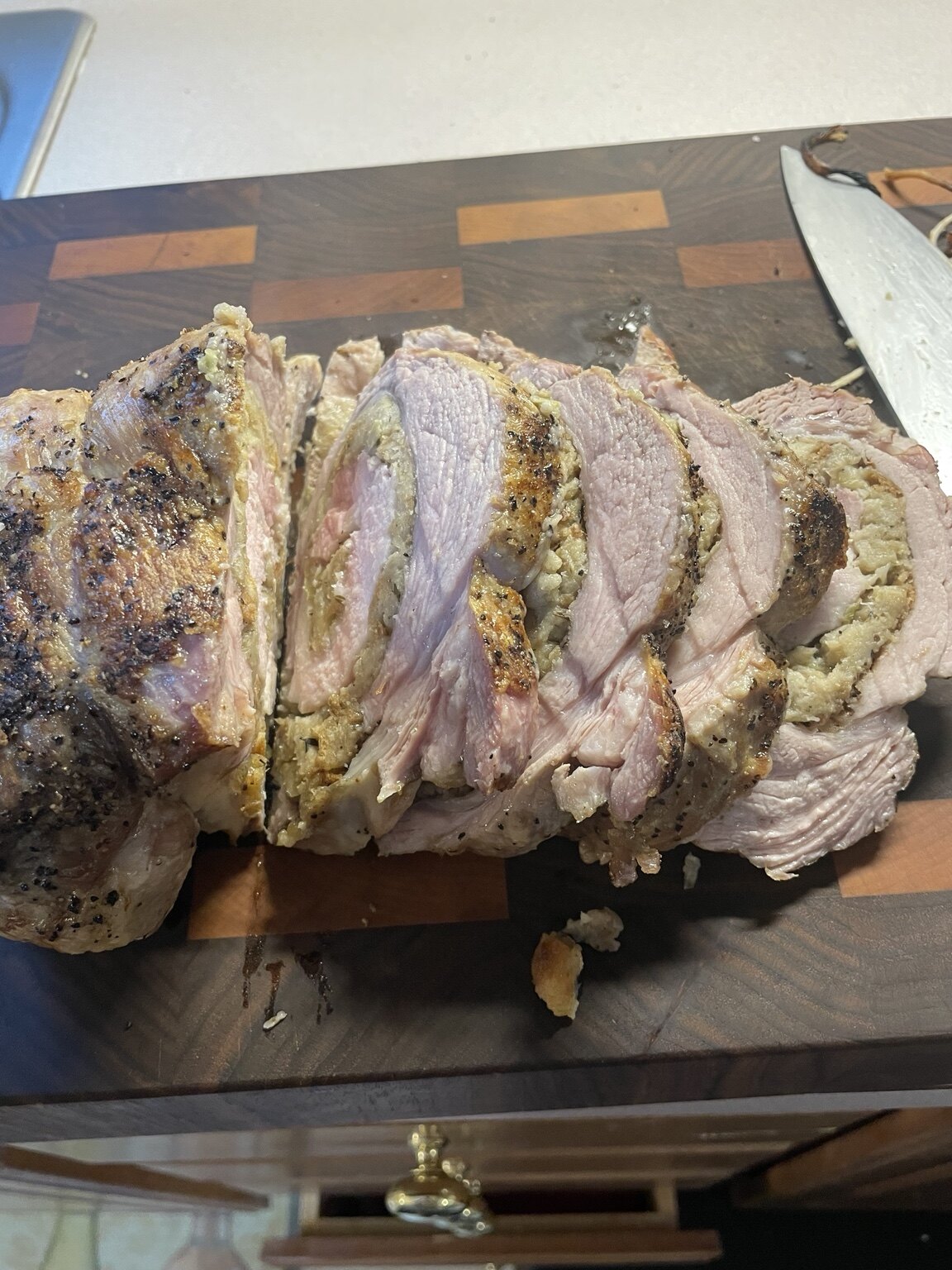 The finished stuffing-rolled pork loin sliced on a butcher-block cutting board