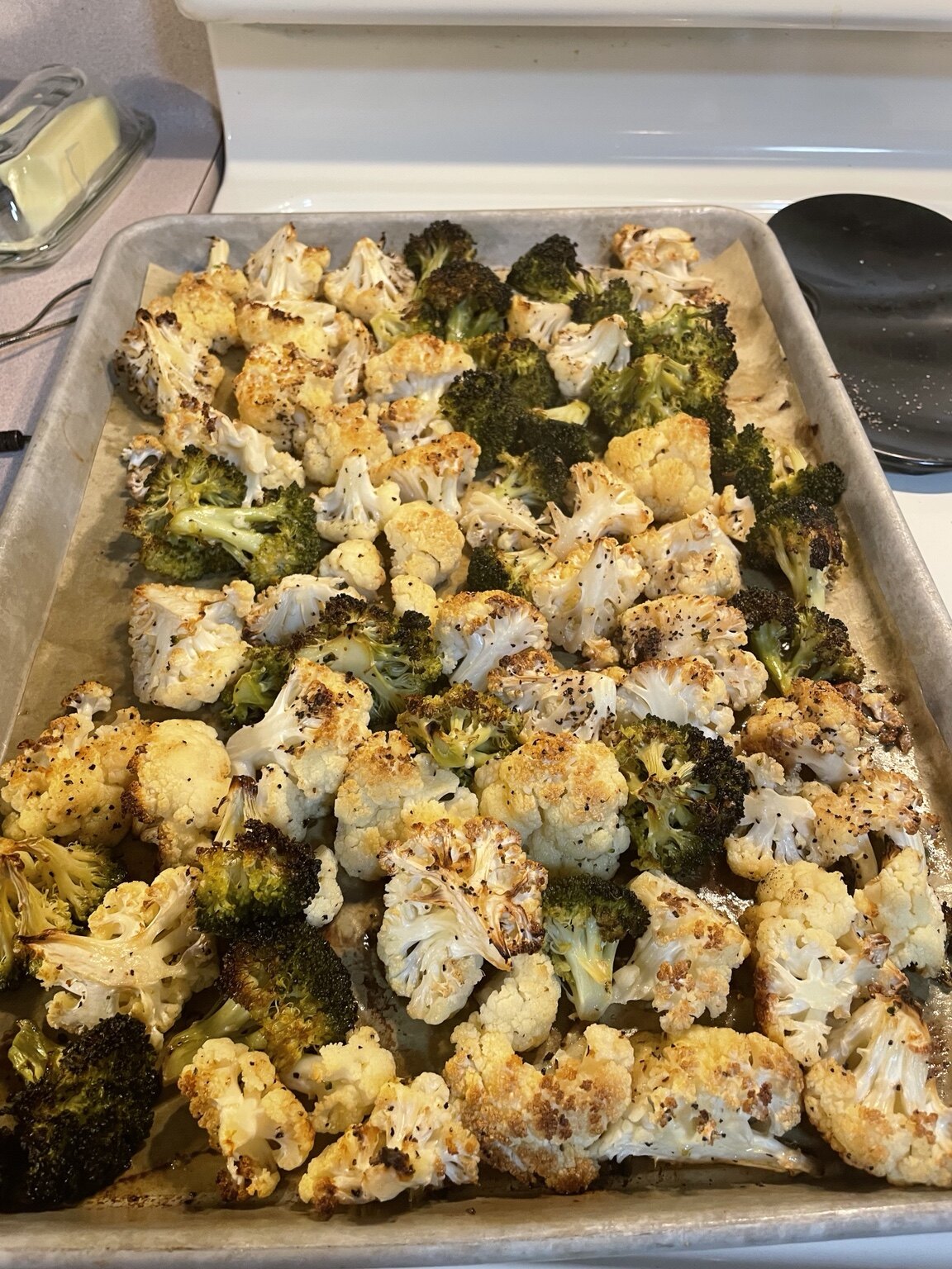 Roasted broccoli and cauliflower browned across a sheet pan